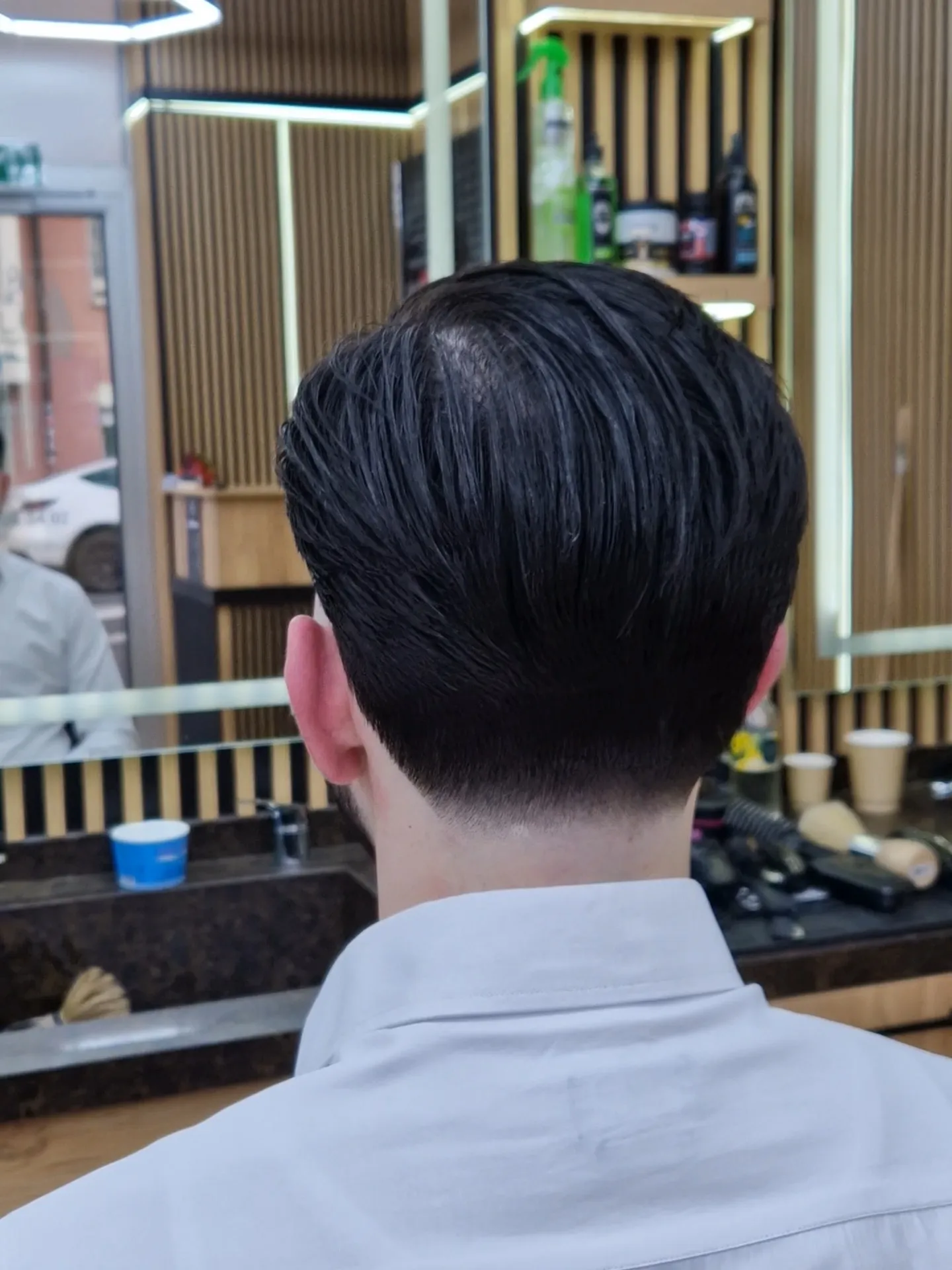 Coupe classique côté nuque, finition nette, devant le miroir à cadre laiton