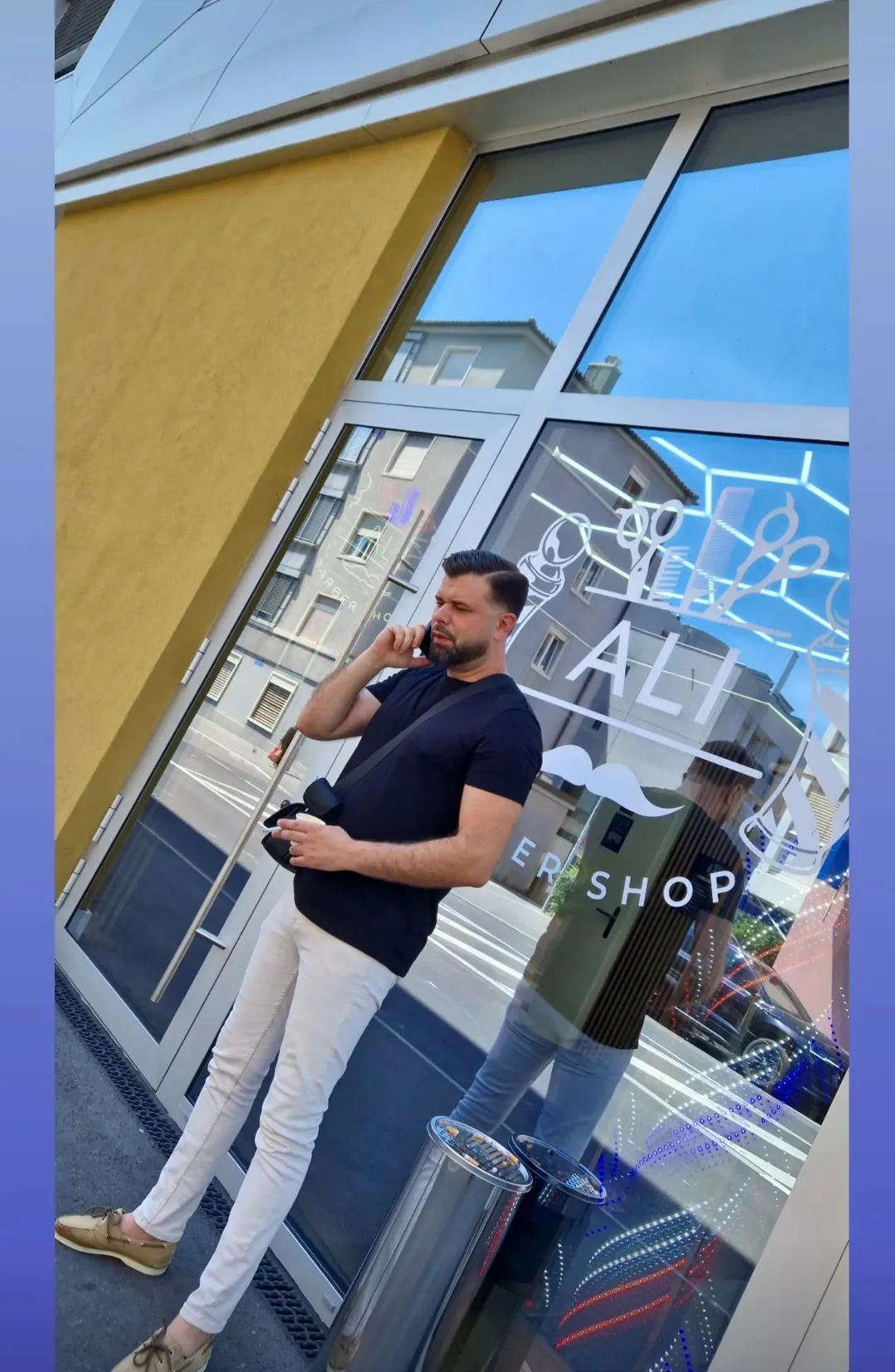 La vitrine du salon avec le lettrage « Ali Barber Shop » et ses illustrations de ciseaux