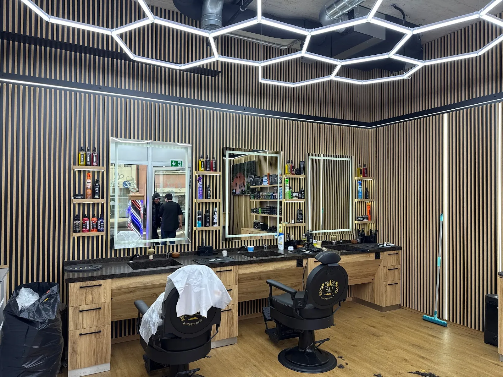 Vue du salon : canapés Chesterfield noirs, pole de barbier et espace de coupe